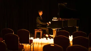 Pianista widziany zza rzędów czerwonych krzeseł